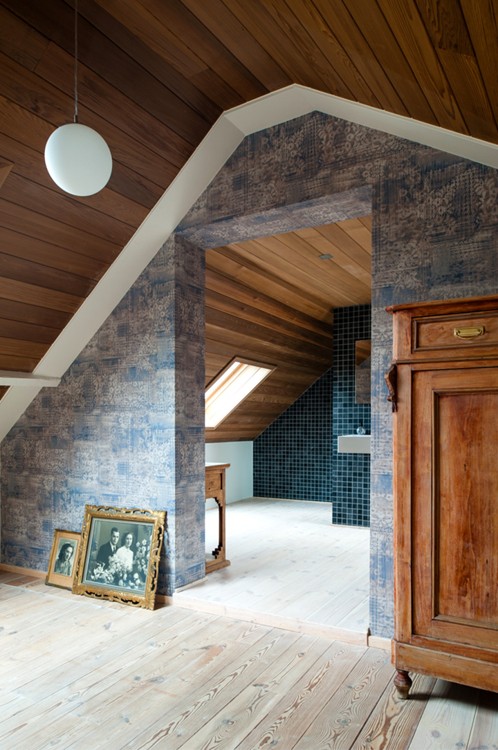 Close-up van  zolderkamer met ingewerkte badkamer. Behang met een verweerde look in blauwe tint 