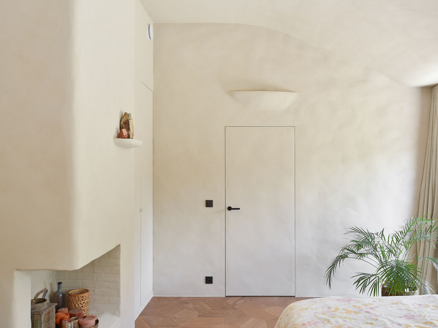 Stijlvolle slaapkamer met ingewerkte deur, afgewerkt met natuurlijke technieken zoals clay structure, Mortex, Aqua sensa® en beton ciré.