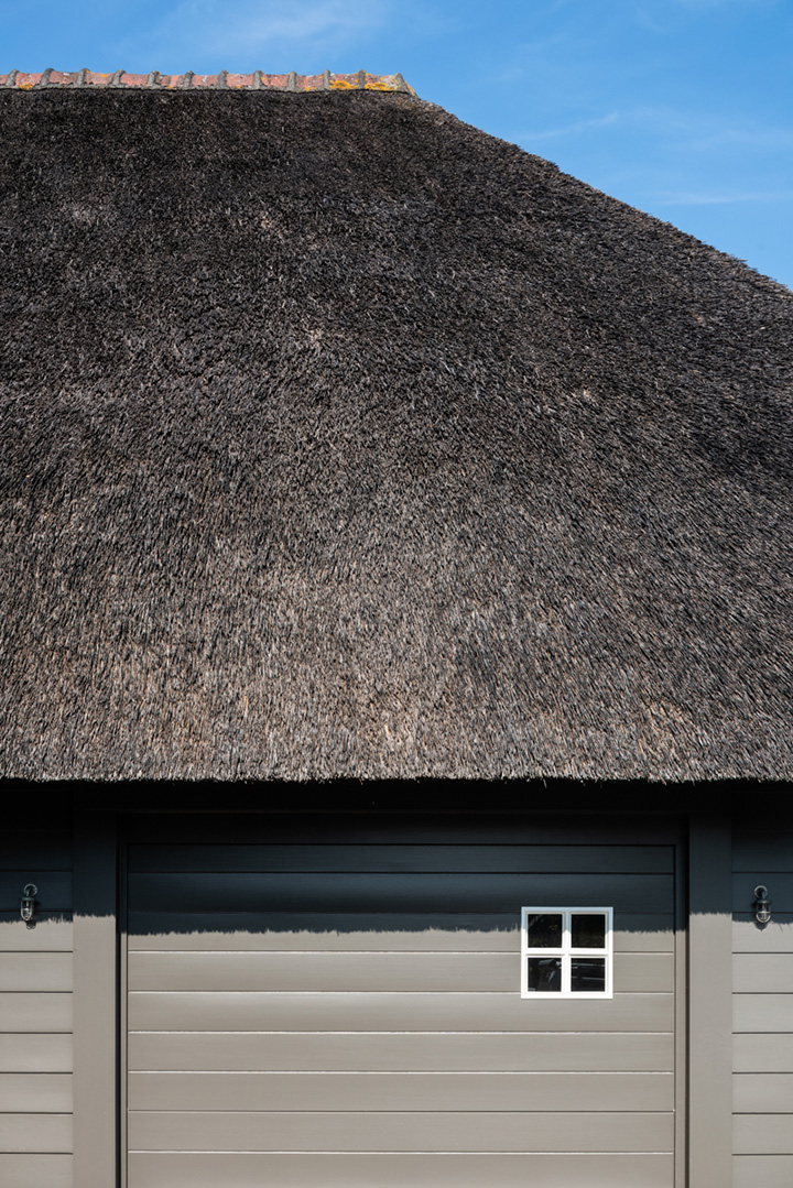 Close-up van taupe geschilderde garage met rieten dak in Knokke.
